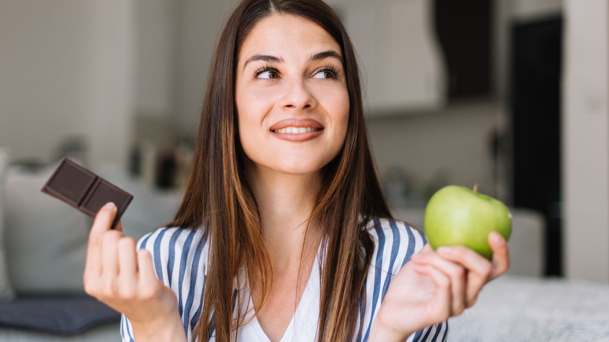 woman choosing between chocolate and apple
